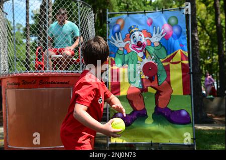Un enfant jette un ballon à l'attraction de la citerne Dunk sur la base Elizabeth City, Caroline du Nord, le 4 août 2022. Le dunk Tank était l'une des nombreuses attractions de la fête de la Garde côtière. Banque D'Images