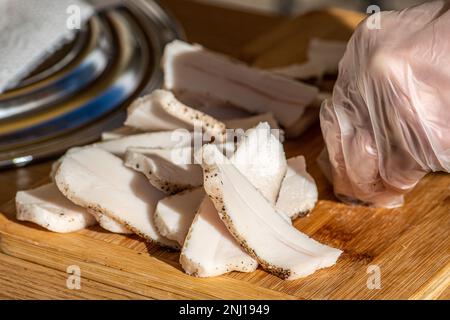 Morceaux de lard ou de bacon, tranchés finement pour la consommation, sur une planche à découper en bois dans un marché de la nourriture de rue, gros plan Banque D'Images