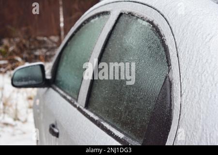 Un gros plan d'une voiture avec des fenêtres et des portes gelées après une tempête de verglas en hiver. Dégivrage d'une serrure de voiture. Banque D'Images