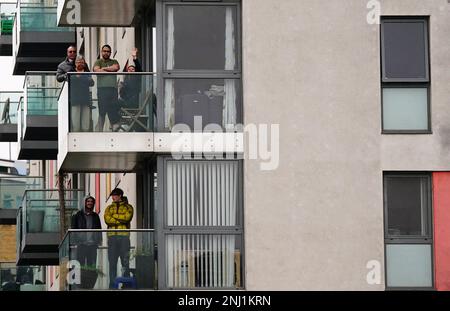 Les gens qui regardent le roi Charles III arriver pour une visite au projet Felix à Poplar, dans l'est de Londres, pour reconnaître le personnel, les bénévoles et les organisations partenaires qui travaillent à fournir des repas à certaines des personnes les plus vulnérables de Londres. Date de la photo: Mercredi 22 février 2023. Banque D'Images