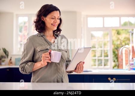 Femme mature avec utilisation de la tablette numérique à la maison pour réserver des vacances ou faire des achats Banque D'Images