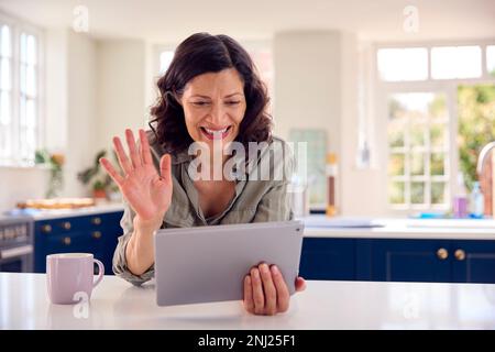 Femme mature utilisant une tablette numérique à la maison pour passer un appel vidéo Banque D'Images