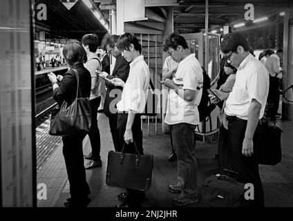 Tokyo, Japon - sept, 2017: Les gens qui attendent le train sur la ligne alors regardant leurs téléphones à la gare de Shinjuku, qui est l'une des plus achalandées Banque D'Images