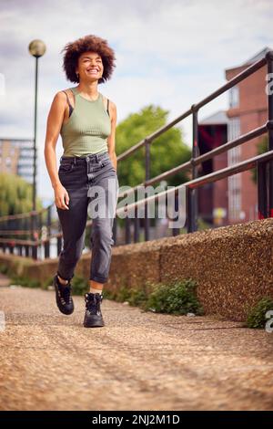 Souriante jeune femme en plein air riant pendant qu'elle marche à travers la ville Banque D'Images