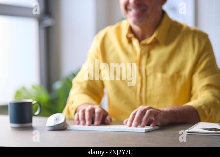 Gros plan de l'homme tapant sur le clavier de l'ordinateur assis au bureau Banque D'Images