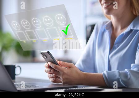 Femme utilisant un téléphone portable avec un recouvrement graphique pour laisser un examen en ligne positif 5 étoiles Banque D'Images