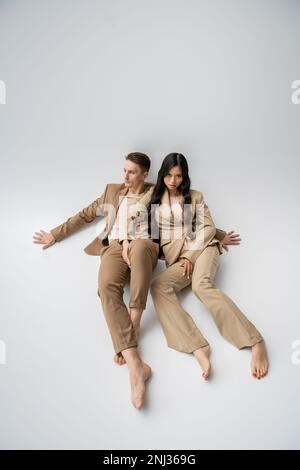 couple multiethnique pieds nus dans une tenue tendance sur fond gris, image de stock Banque D'Images