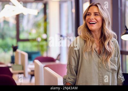 Femme d'affaires mature debout près de la partition dans Open Plan Office Banque D'Images