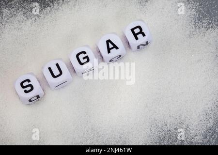 Sucre écrit en dés de lettre sur les granules de sucre blanc Banque D'Images