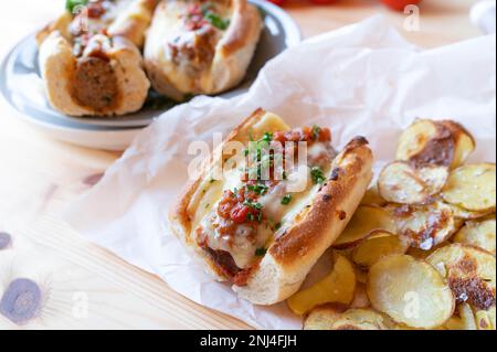 Sandwich meatball avec sauce tomate, fromage fondu et chips de pommes de terre faites maison sur la table de cuisine Banque D'Images