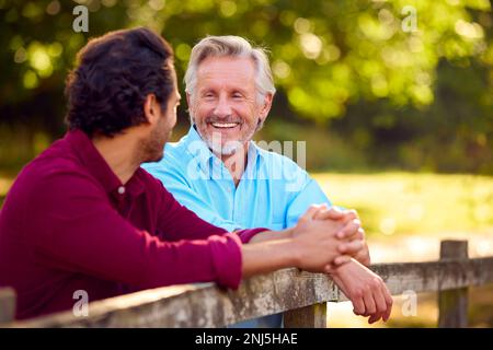 Père mûr avec race mixte son adulte penchée sur Fence Marche à pied dans la campagne Banque D'Images