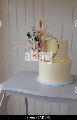 Magnifique, simple gâteau de mariage à deux niveaux avec cerceau de fleurs naturelles à décorer, Derbyshire, Royaume-Uni Banque D'Images