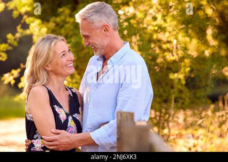 Amoureux couple d'âge mûr se penchant sur Fence sur une promenade dans la campagne ensemble Banque D'Images