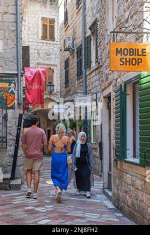 Touristes occidentaux et femme musulmane / shopping muslima dans une ruelle étroite dans le centre de la vieille ville vénitienne de la ville Kotor, sud-ouest du Monténégro Banque D'Images