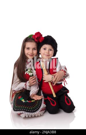 Garçons et filles bulgares en costumes traditionnels folkloriques avec fleurs printanières en forme de goutte d'eau et bracelet en laine martenitsa, symbole de Baba Marta Banque D'Images