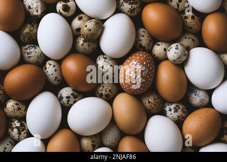 Joyeux pâques écrit blanc oeuf de poulet sur pile d'oeufs. Pile d'œufs de poulet brun et blanc avec œufs de caille Banque D'Images