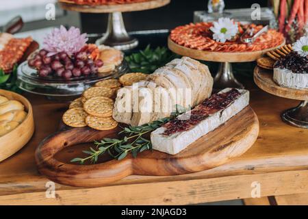 Une variété de hors-d'œuvre, y compris de la viande, du fromage et des fruits, disposés sur plusieurs assiettes et plateaux sur une table en bois Banque D'Images