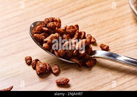 Une cuillère remplie de céréales au chocolat sur une surface en bois Banque D'Images