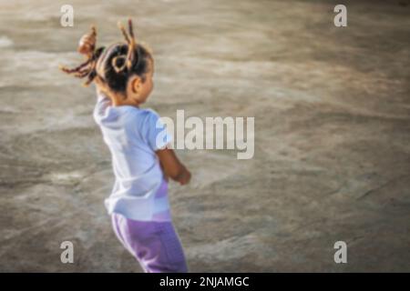 Photo floue de petite fille brésilienne du dos courant et jouer avec des tresses dans le vent, fille défocused, photo avec espace réservé pour l'écriture Banque D'Images