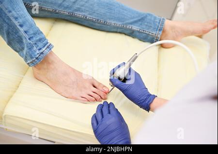 la podologue est une femme utilisant un laser pour traiter l'onychomycose - une maladie fongique des ongles. Cosmétologie matérielle Banque D'Images