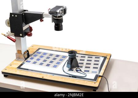 Prise de vue horizontale d'un appareil photo sur un support de copie pour copier les 35mm anciennes diapositives. Sur le support de copie se trouve une boîte lumineuse avec des diapositives et une loupe. Banque D'Images