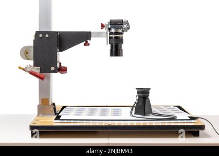 Vue latérale horizontale d'un appareil photo sur un support de copie prêt à copier les 35mm anciennes diapositives. Sur le support de copie se trouve une boîte lumineuse avec des diapositives et une loupe. Banque D'Images