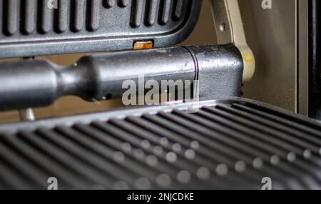 Grille électrique noire, fond texturé. La surface du gril électrique. Pollution de la surface du poêle électrique. Gros plan d'une maison Banque D'Images