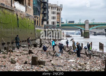 Les mudlarkers bouchent sur la rive rocheuse de la Tamise à marée basse à Londres, en Angleterre Banque D'Images