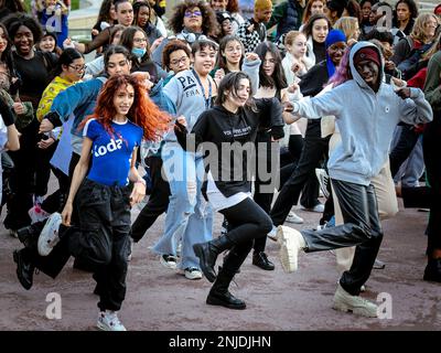 Un groupe diversifié de jeunes danseurs participent à une joyeuse performance flash mob, remplissant la rue de mouvement, d'énergie et d'unité Banque D'Images