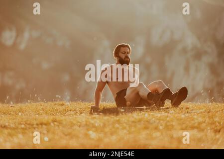 Un homme faisant des exercices d'abs sur une montagne Banque D'Images