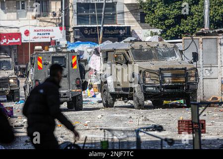 Naplouse, Palestine. 22nd févr. 2023. Des jeunes Palestiniens jettent des marchandises et des légumes sur les véhicules de l'armée israélienne lors des affrontements au marché des légumes dans la vieille ville de Naplouse, en Cisjordanie occupée. Des affrontements ont éclaté entre les Palestiniens et l'armée israélienne après que l'armée israélienne ait éclaté dans le refuge dans lequel des hommes armés palestiniens des groupes Lions de Den se cachaient dans la vieille ville de Naplouse, tuant quatre hommes armés et six civils qui étaient présents sur le marché pendant le raid. Crédit : SOPA Images Limited/Alamy Live News Banque D'Images