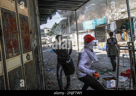 Naplouse, Palestine. 22nd févr. 2023. Des jeunes Palestiniens jettent des marchandises et des légumes sur les véhicules de l'armée israélienne lors des affrontements au marché des légumes dans la vieille ville de Naplouse, en Cisjordanie occupée. Des affrontements ont éclaté entre les Palestiniens et l'armée israélienne après que l'armée israélienne ait éclaté dans le refuge dans lequel des hommes armés palestiniens des groupes Lions de Den se cachaient dans la vieille ville de Naplouse, tuant quatre hommes armés et six civils qui étaient présents sur le marché pendant le raid. Crédit : SOPA Images Limited/Alamy Live News Banque D'Images