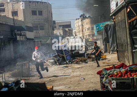 Naplouse, Palestine. 22nd févr. 2023. Un véhicule militaire israélien a été vu à la poursuite de jeunes Palestiniens lors des affrontements sur le marché des légumes dans la vieille ville de Naplouse, en Cisjordanie occupée. Des affrontements ont éclaté entre les Palestiniens et l'armée israélienne après que l'armée israélienne ait éclaté dans le refuge dans lequel des hommes armés palestiniens des groupes Lions de Den se cachaient dans la vieille ville de Naplouse, tuant quatre hommes armés et six civils qui étaient présents sur le marché pendant le raid. (Photo de Nasser Ishtayeh/SOPA Images/Sipa USA) crédit: SIPA USA/Alay Live News Banque D'Images