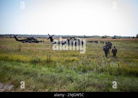 ÉTATS-UNIS Soldats de l'armée qui mènent les États-Unis Parcours de l'armée Pathfinder, marchez dans un champ en passant devant LES hélicoptères UH-60 Black Hawk au Camp Dodge à Johnston, Iowa, le 7 septembre 2022. Les chasseurs de navires de l'armée sont formés pour fournir de l'aide à la navigation et des services consultatifs aux aéronefs militaires dans les zones désignées par les commandants d'unités appuyés. Au cours du cours Pathfinder, les étudiants sont formés à l'orientation de l'aéronef, à l'évacuation aéro-médicale, à l'assaut de combat rapproché, aux procédures de communication sol-air, aux opérations du centre de contrôle, aux trois phases d'une opération de chargement de harnais, à la zone d'atterrissage de l'hélicoptère et à l'opération de la zone de ramassage Banque D'Images