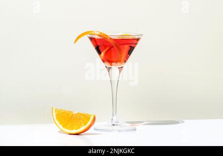 Boisson alcoolisée Martinez avec vermouth rouge, liqueur, orange amère, zeste et glace. Fond beige clair, lumière dure, motif ombre. Minimale Banque D'Images