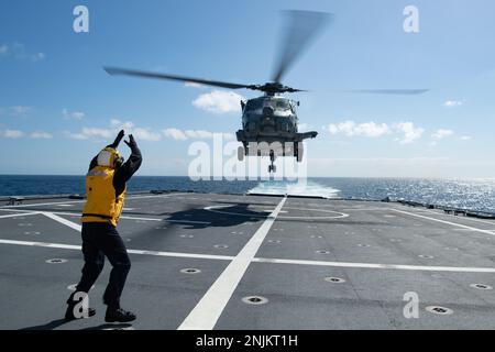 230218-N-MK318-1417 OCÉAN PACIFIQUE EST (18 févr. 2023) technicien Sonar (surface) 2nd classe Quinn Vaticano, un équipage bleu marin à bord du navire de combat littoral USS Independence-variant Mobile (LCS 26), signale à la main un hélicoptère MH-60R, attaché à l’Escadron de frappe maritime hélicoptère 49 (HSM 49), pour décoller du pont de vol du navire, 18 février. Les navires de combat littoraux sont des combattants de surface rapides, parfaitement habités et adaptés à la mission, qui opèrent dans des environnements proches du rivage et en pleine mer, ce qui permet de vaincre les menaces côtières du 21st siècle. Mobile est actuellement en cours de réalisation d'opérations de routine aux États-Unis Banque D'Images