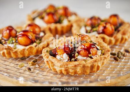 Tartelettes au melon, mascarpone et pistaches sur une plaque transparente. Gros plan. Banque D'Images