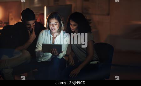 Des entrepreneurs prospères de jour et de nuit. un groupe de collègues utilisant une tablette numérique ensemble pendant une nuit de travail. Banque D'Images