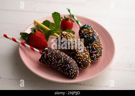 Bananes enrobées de chocolat noir et recouvertes de caramel décoratif. Banque D'Images