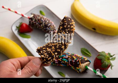 Bananes enrobées de chocolat noir et recouvertes de caramel décoratif. Banque D'Images