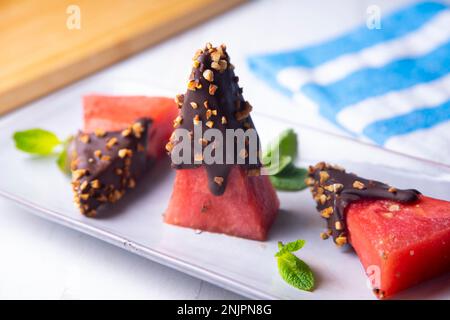 Morceaux de pastèque fraîche trempée dans du chocolat et recouverte d'amandes caramélisées. Banque D'Images