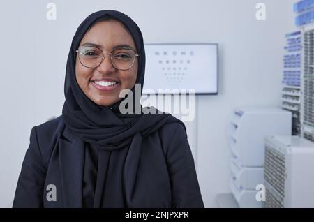 Hijab, heureuse femme musulmane et portrait optométriste dans un cabinet de médecin prêt pour le test oculaire avec carte. Soins de santé, bien-être des yeux et professionnel de la clinique fier Banque D'Images