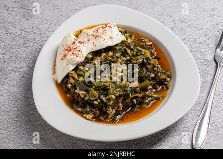 Repas traditionnel aux épinards turcs avec riz et viande hachée et yaourt sur une assiette en porcelaine blanche Banque D'Images