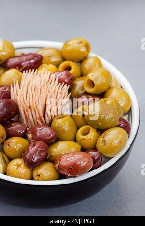 Mélange d'olives marinées dans un bol à cocktail gris Banque D'Images