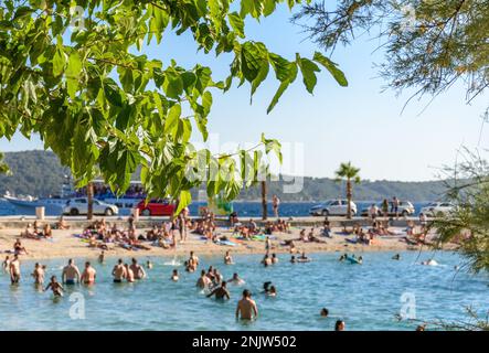 Les gens se détendent et bronzer à la plage par une journée ensoleillée en été à la plage de Kasjuni à Split, Croatie Banque D'Images