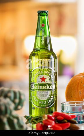 Bouteille verte en verre de bière Heineken placée sur le comptoir sur fond flou Banque D'Images