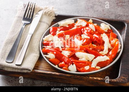 Salade de morue Esgarraet aux poivrons rouges grillés, à l'ail et à l'huile d'olive sur l'assiette sur la planche de bois. Horizontale Banque D'Images