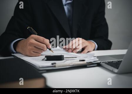 Homme d'affaires du concessionnaire automobile signant le document d'assurance automobile. Concept de prêt et d'assurance pour l'achat de voitures. Banque D'Images