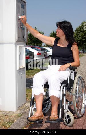 femme en fauteuil roulant au guichet de stationnement Banque D'Images