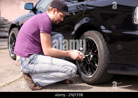 changement de pneu, jeune homme change les pneus d'hiver en pneus sommer, photo de série 9/9 Banque D'Images